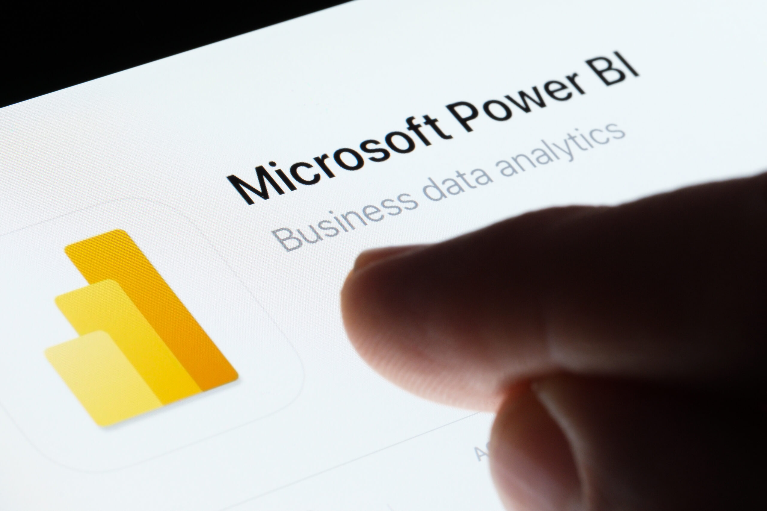 Microsoft Power BI app seen in App Store on the screen of ipad and blurred finger pointing at it. Business data analytics. Stafford, United Kingdom, May 6, 2023