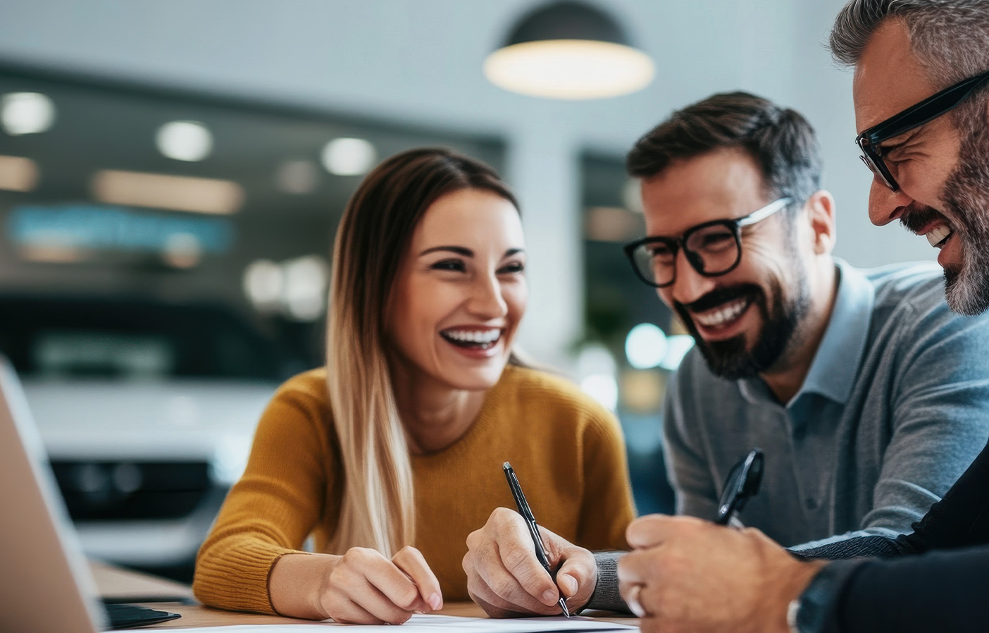 Dealership professionals reviewing and signing warranty documents at a desk, representing warranty reimbursement and compliance services for automotive dealerships.