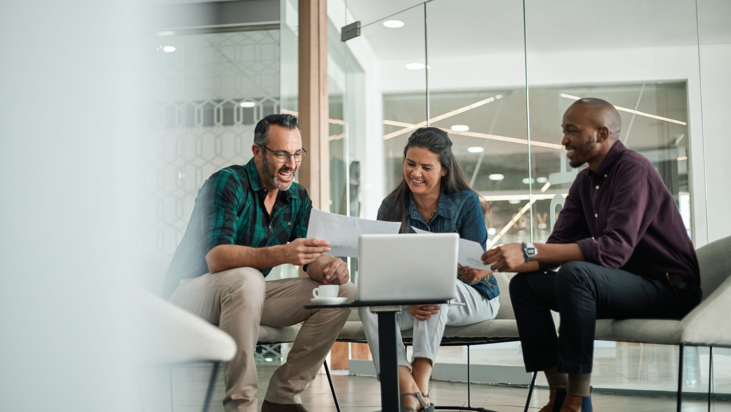 Three people sitting around a computer in a conference room.