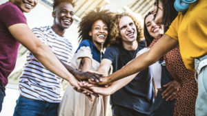 Multiracial happy young people stacking hands outside - Diverse