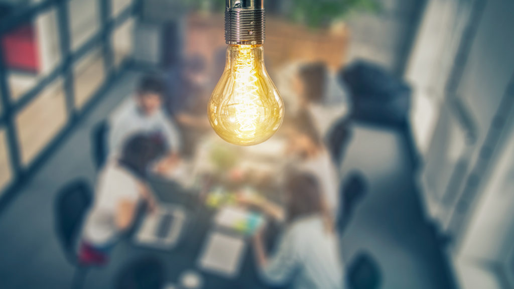 Unleash the full potential of hybrid work - team meeting under a lightbulb