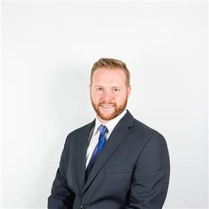 White Male in a grey suit with white shirt, posing for professional headshot.