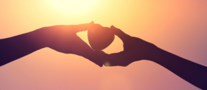 Hand giving heart to another. Love, donation, gift, charity concept.