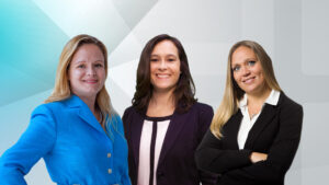 Three women in business attire, smiling at the camera.