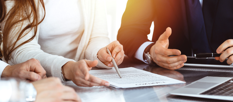 Business people discussing contract while working together in sunny modern office.