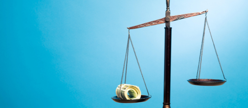 A gold balance scale with a light blue background.