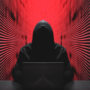 Cyber security hacker sitting in front of a laptop depicting stealing personal data with a red technology background.