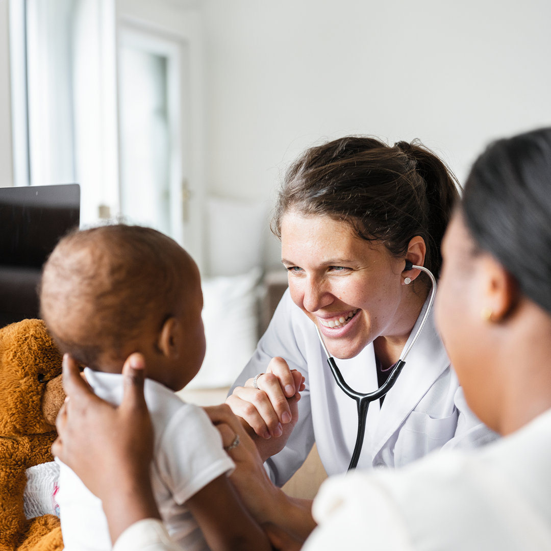 Physician smiling at a baby during an office visit.