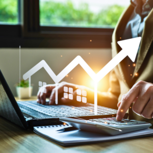 An insurance agent is appraising a property's valuation using a laptop and calculator.