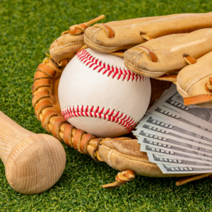 A leather baseball mitt with a baseball and money inside of it, on a green field.