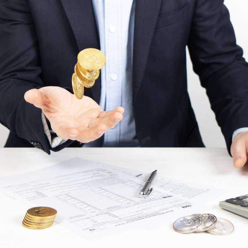 Taxation: a man fills out a tax return and tosses cryptocurrency coins in his hand.