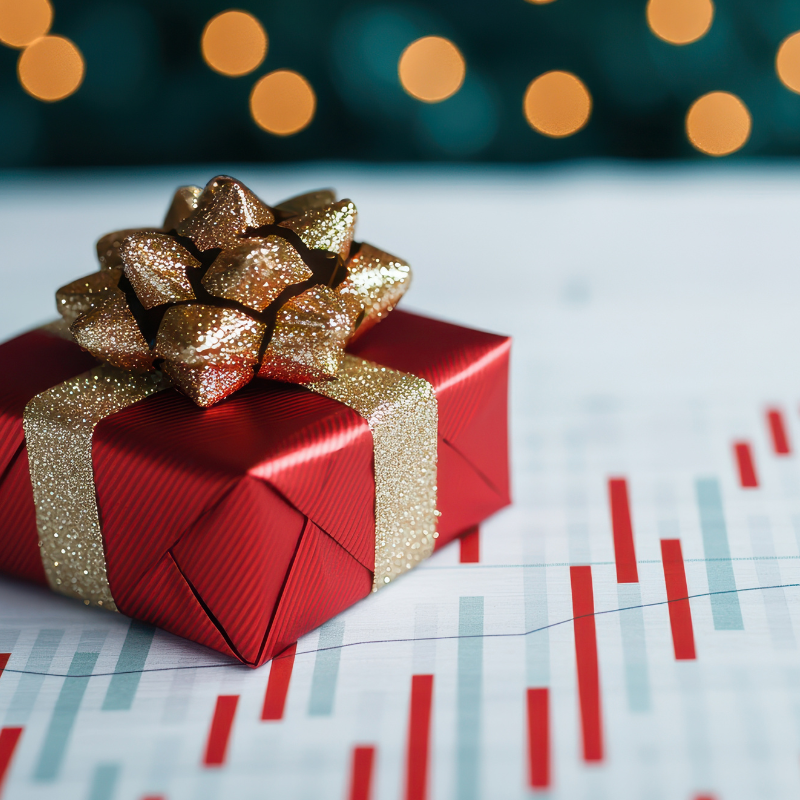 festive red gift box with golden bow sits on financial graph, symbolizing end of year sales and holiday cheer.