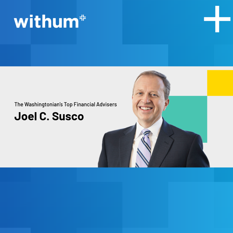 Joel Susco, smiling in a professional headshot. He is wearing a black suit with a white collar shirt and a striped blue tie. The background consist of different shades of blue.