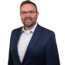 Profile headshot of Kyle Grunstra in a blue suit coat.