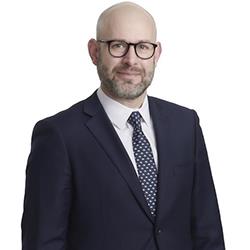 Profile headshot of Ryan Caster in a black suit coat.