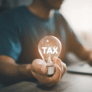 Man hand holding light bulb while working on laptop and mobile phone. With tax messages, conveys SALT tax deductions at the end of the year.