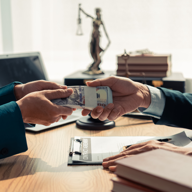 Two hands exchanging payment and showcasing the impact of Guaranteed Payments on Law Firm Finances for a partner.