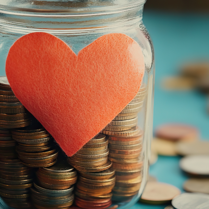 a jar filled with coins and a heart symbolizing charity and donations