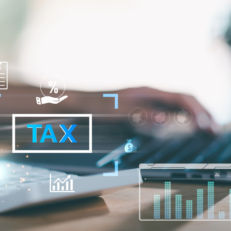 A person types on a laptop with digital tax-related graphics and icons overlaying the image, including the word "TAX" and financial symbols.