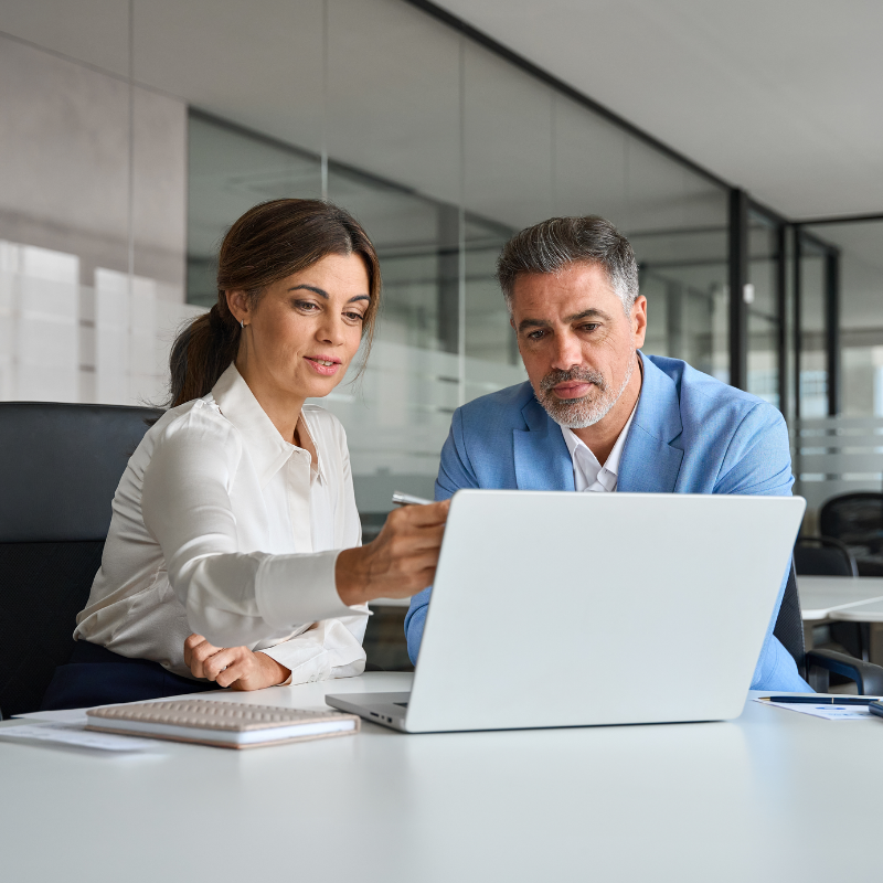 two business collegues working together analyzing data on a laptop.