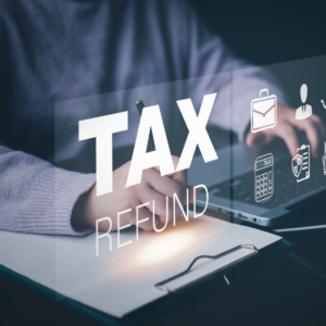 Businessman using a pen to write a notebook with TAX REFUND and refund tax of duty taxation business, graphs and chart being demonstrated on the screen media, tablet pc and selecting tax refund.