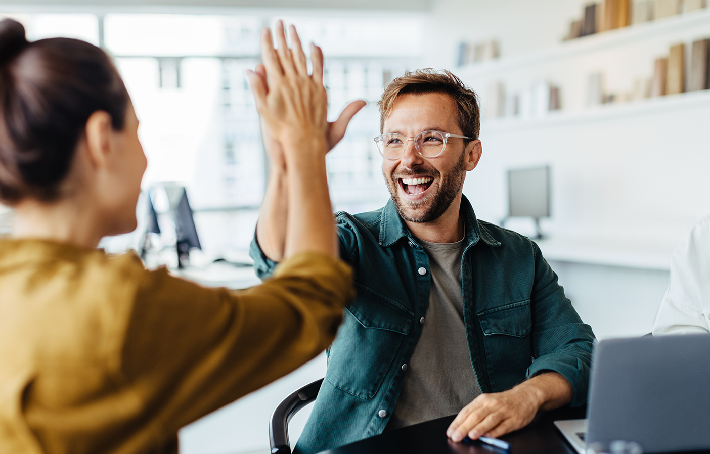 Two team members high fiving in a business setting.