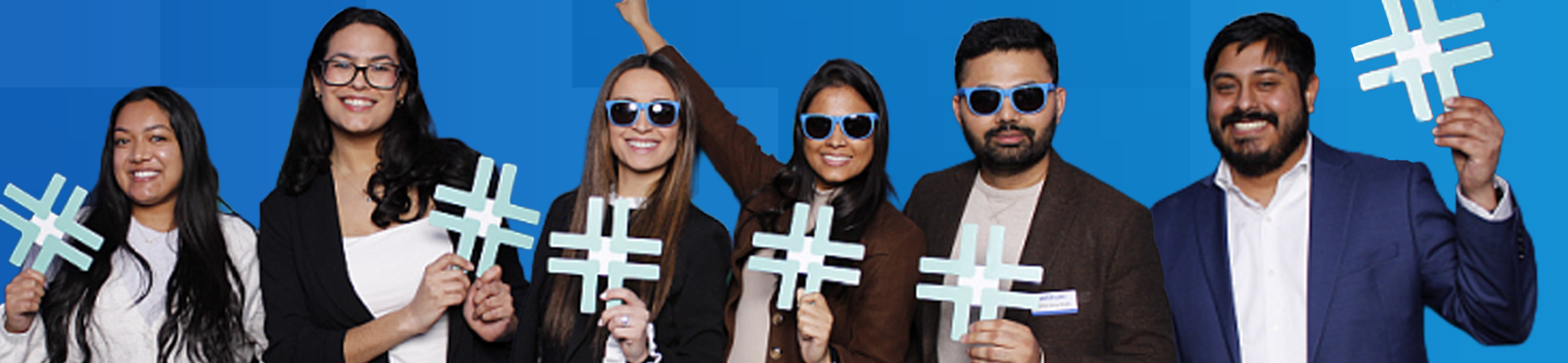 Withum team members holding plus signs at event.