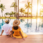 two hotel guests on vacation sitting by the pool watching the sunset.