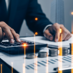 business man doing his taxes with calculator and stack of coins.