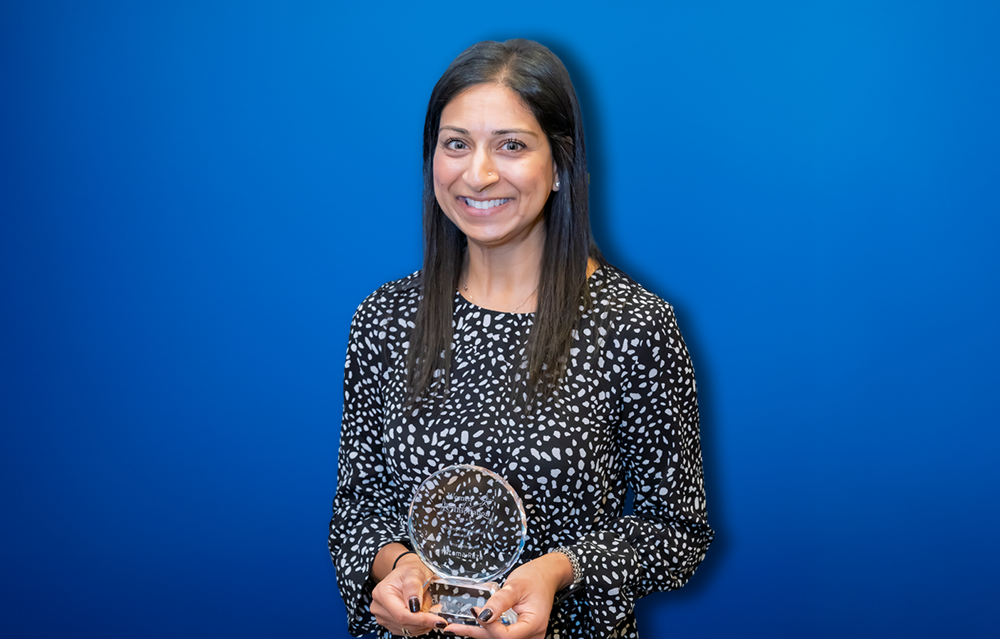 Fatema Raza smiling and holding her NJ Chamber of Commerce Young Professional Award.