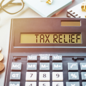 Word TAX RELIEF. Written on a calculator on an office desk.